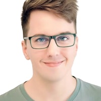 a young man with glasses smiling in front of a white background